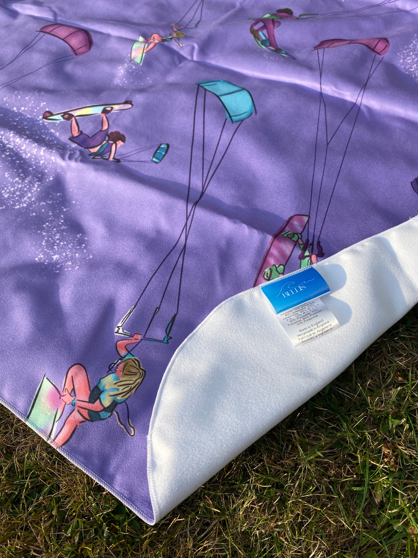 Purple towel with kite designs on grass